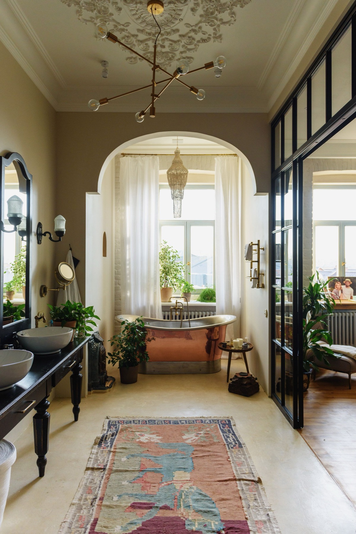 A period bathroom with a copper roll-top bath under an arch and a patterned tiled floor