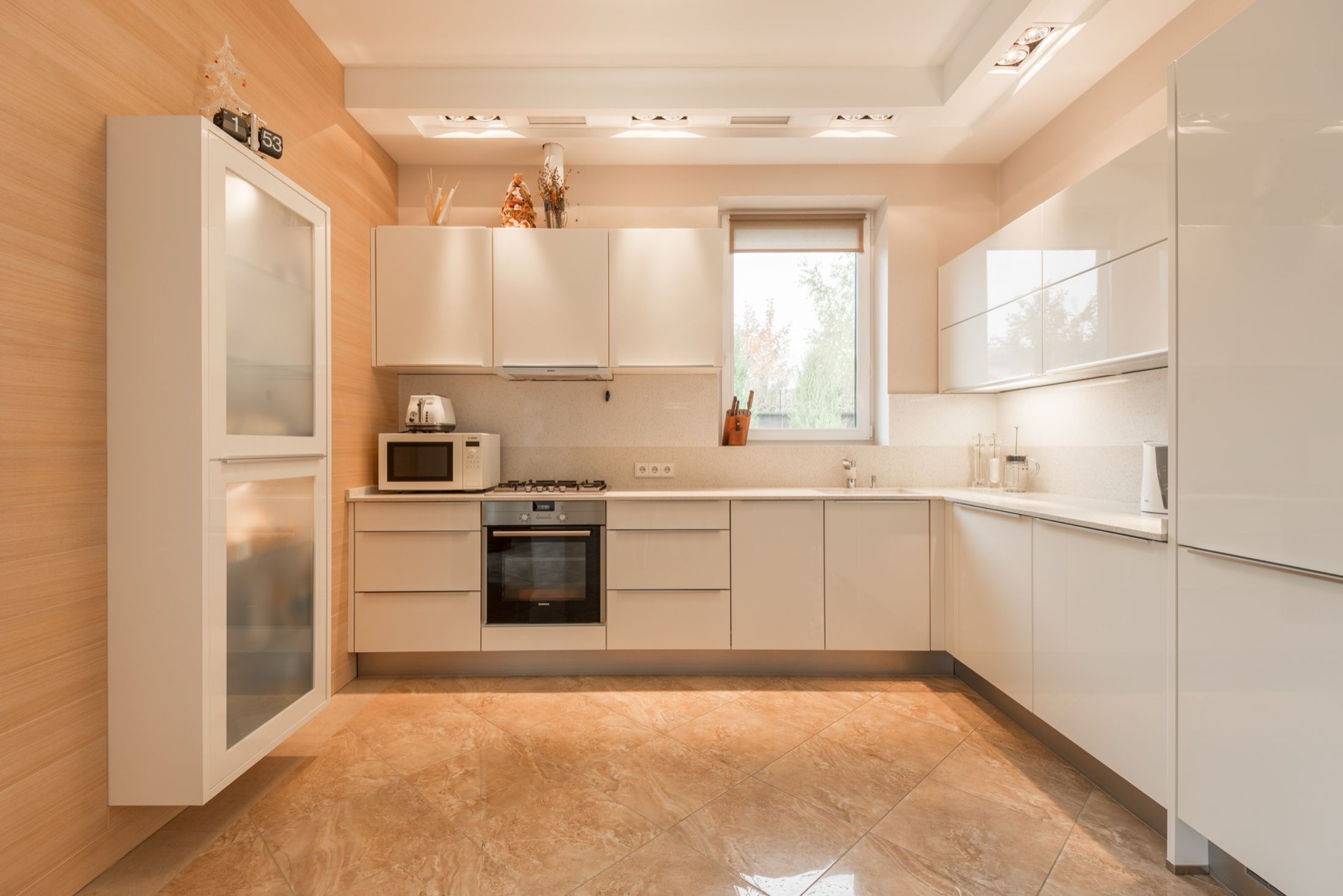 A kitchen with a warm stone-effect tiled floor running through the room