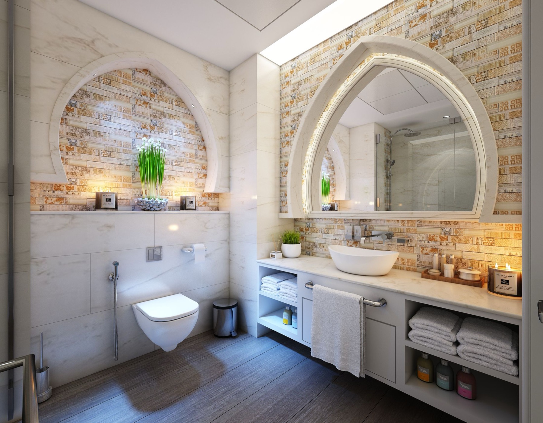 A bathroom finished in warm stone-effect tiling, with an arched tiled niche and a wall-hung basin