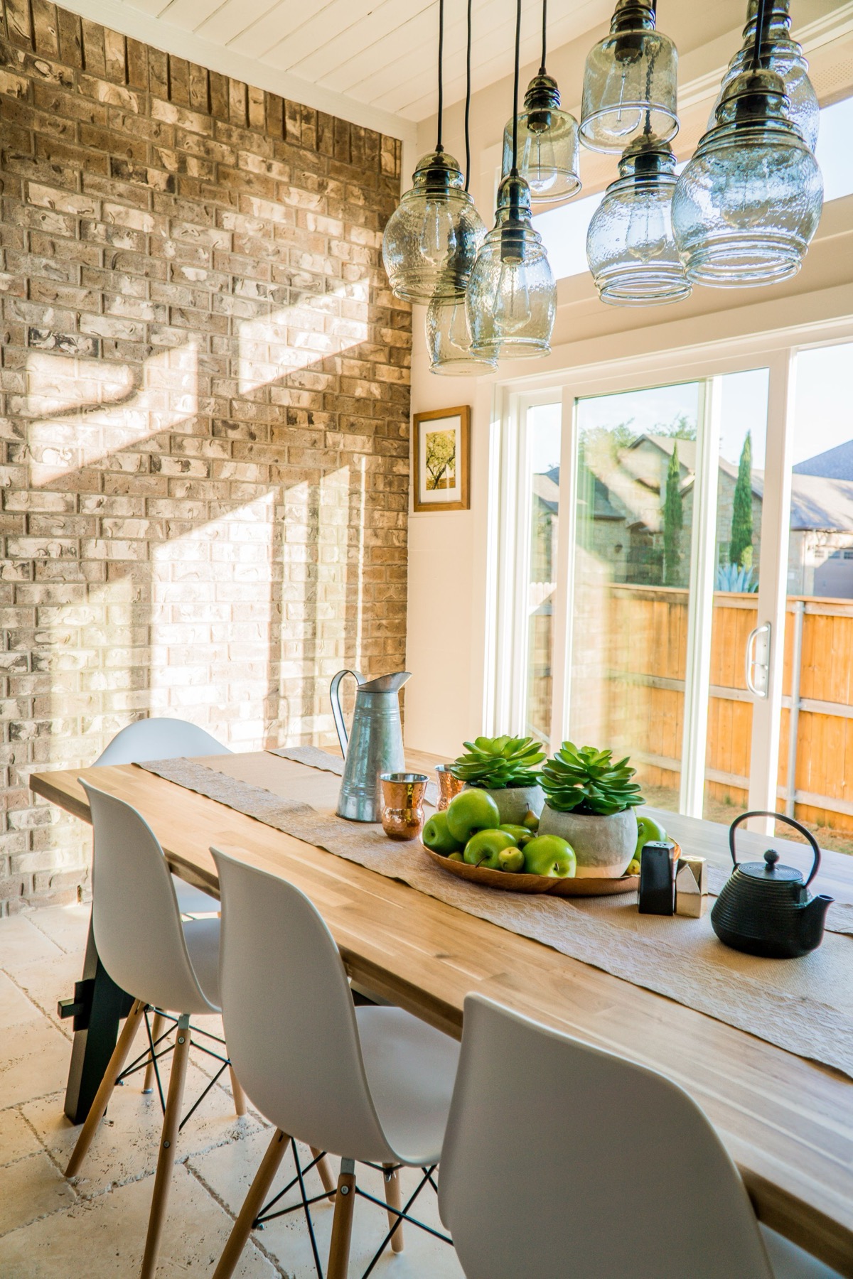 A bright dining space with an exposed brick wall and a stone-tiled floor