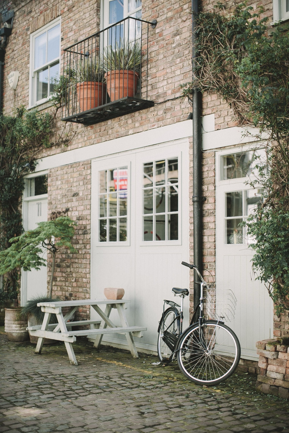 A red-brick terrace with white timber windows on a cobbled street, typical of the housing around Altrincham